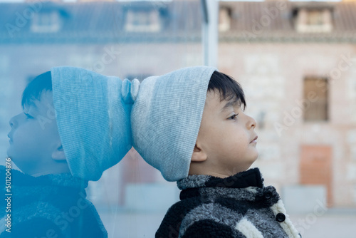 child leaning against a blue wall pensive, daydreaming