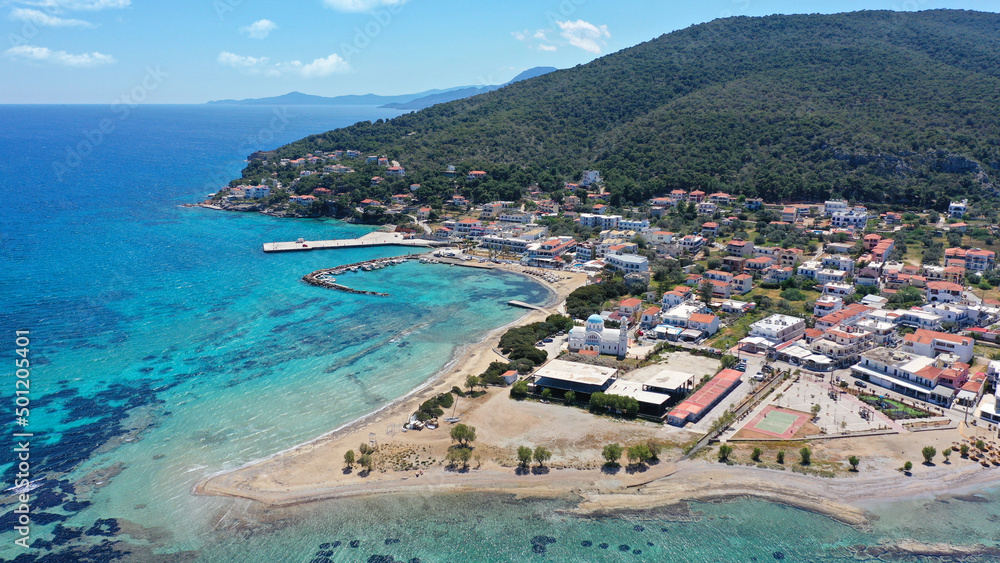 Aerial drone photo of iconic picturesque village, main port and beautiful turquoise beaches of Skala featuring landmark church of Agioi Anargiroi, Agistri island, Saronic gulf, Greece