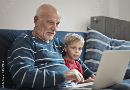 Bild auf Leinwand portrait of grandfather and grandson with a computer in hand