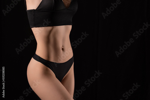 Muscular body of a woman in lingerie on a black background