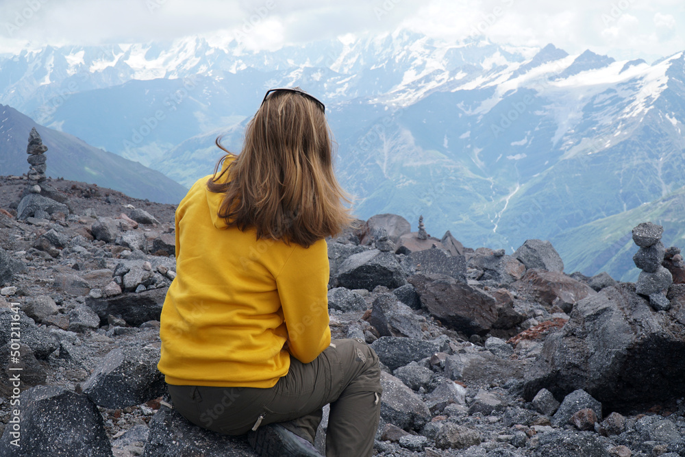Young tourist woman is hiking on the top of the mounting and looking at a beautiful landscape Young tourist woman is hiking on the top of the mounting and looking at a beautiful landscape
