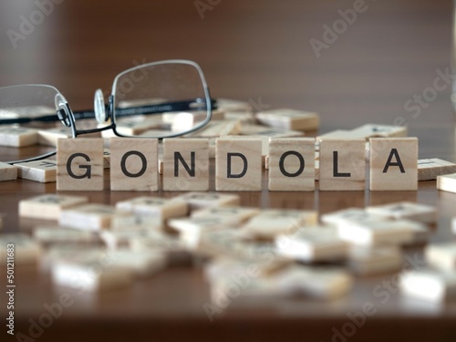 gondola word or concept represented by wooden letter tiles on a wooden table with glasses and a book photo