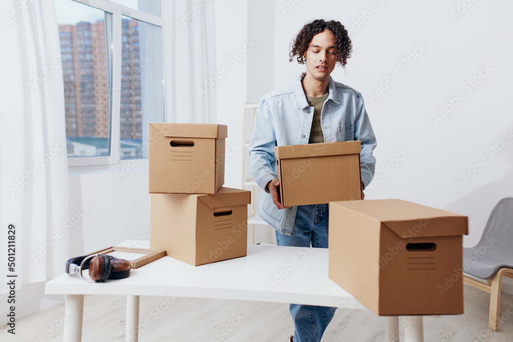 A young man unpacking things from boxes in the room Lifestyle A young man unpacking things from boxes in the room Lifestyle