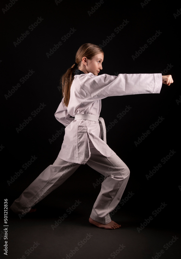 girl in kimono practicing taekwondo on black background. Sports banner. girl in kimono practicing taekwondo on black background. Sports banner.