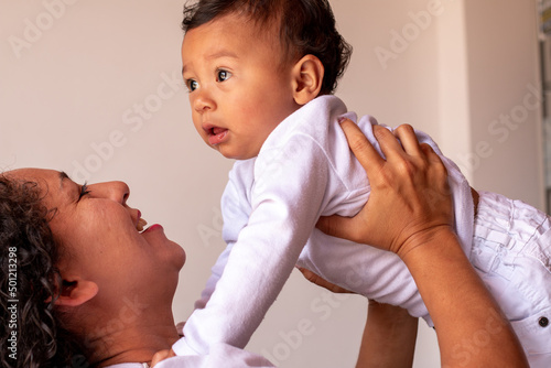 Fényképezés A latin mother raising her beautiful baby on her head and looking at his face