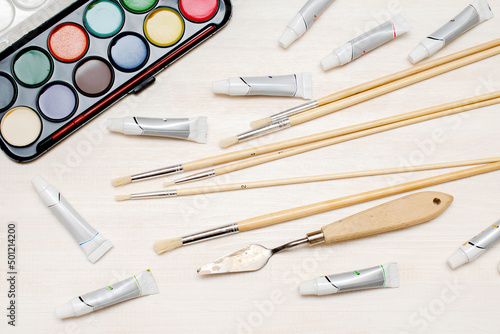 Watercolor oil tubes paints, paintbrushes, palette knife, colorful. Creativity creation process. Artist's stuff on white table.Top view Flatlay of drawing supplies