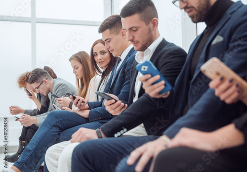 group of young business people looking at their smartphone screens.