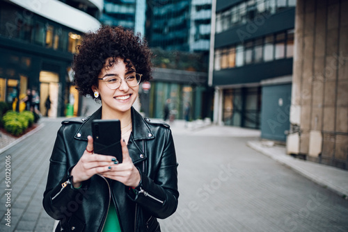 Woman with afro hair using a smartphone outside in the city © Zamrznuti tonovi