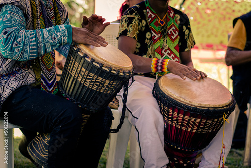 Sao Paulo, SP, Brazil - November 11 2021: Men, with traditional indigenous clothes and handicrafts playing djembe details photo