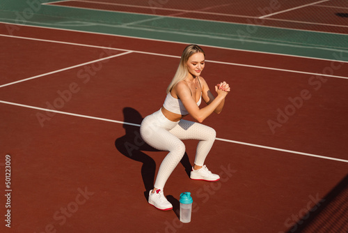 Fit athletic girl sit ups outdoors. Active lifestyle of a young blonde sport woman.