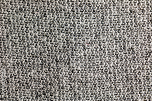 Gray knitted carpet close-up. Textile texture on a gray background. Detailed background from warm yarn. Natural wool fabric, sweater fragment.