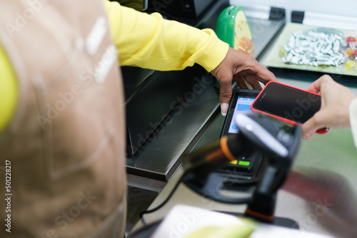 Woman's hands charging a client who pays with her mobile