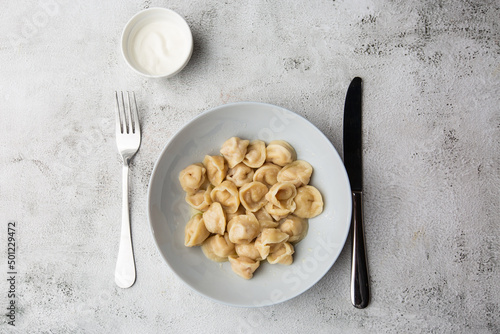 Meat dumplings, homemade russian pelmeni in bowl with sour cream isolated on bright background