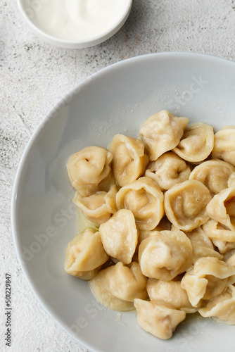 Meat dumplings, homemade russian pelmeni in bowl with sour cream isolated on bright background