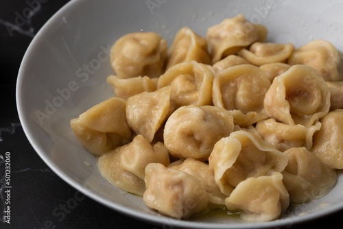 Meat dumplings, homemade russian pelmeni in bowl isolated on black background with clipping path