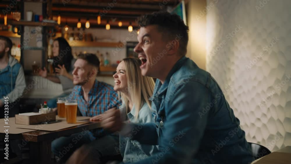 Friends are watching together emotionally watching football on TV in a bar and celebrating the victory of their team after scoring a goal. The scored puck. Fans in the pub Friends are watching together emotionally watching football on TV in a bar and celebrating the victory of their team after scoring a goal. The scored puck. Fans in the pub