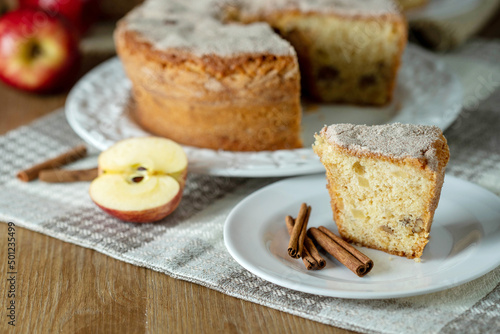 piece of Sponge cake or chiffon cake with apples so soft and delicious sliced ​​with ingredients: cinnamon, eggs, flour, apples on wooden table. Home bakery concept for background and wallpaper