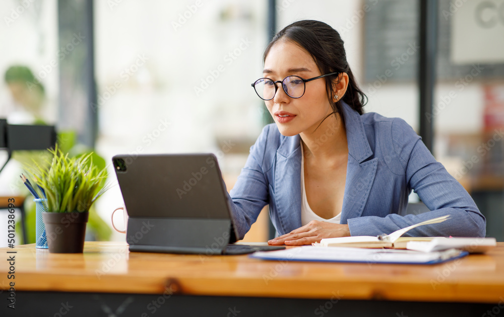 Portrait of smiling pretty young Asian businesswoman in glasses sitting on workplace Portrait of smiling pretty young Asian businesswoman in glasses sitting on workplace