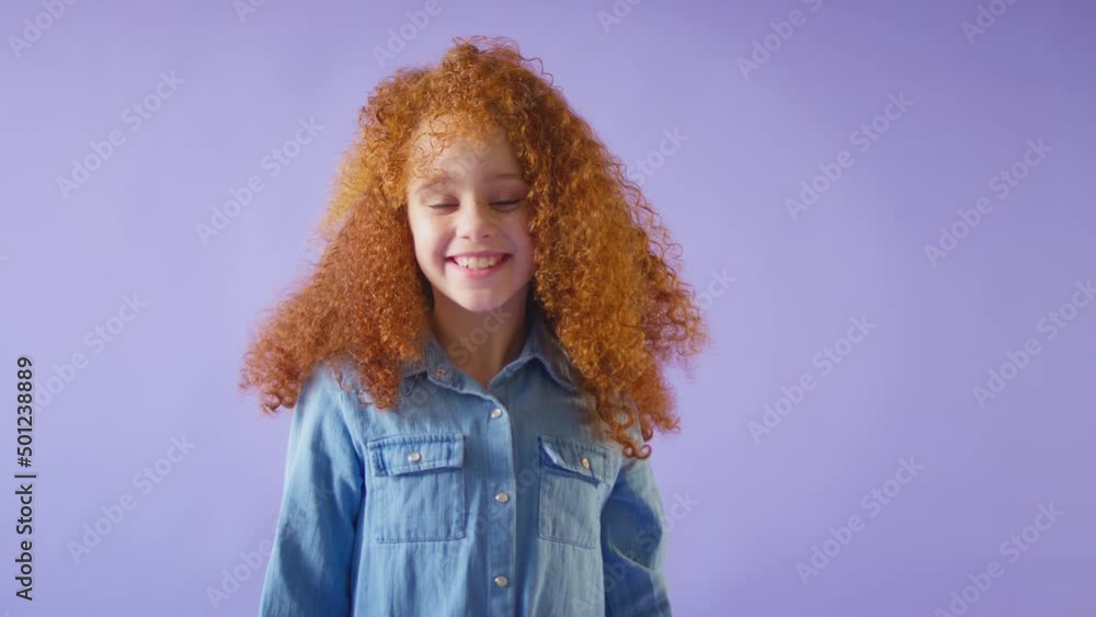 Studio Shot Of Smiling Girl With Red Hair Jumping Into Bottom Of Frame Against Purple Background Studio Shot Of Smiling Girl With Red Hair Jumping Into Bottom Of Frame Against Purple Background