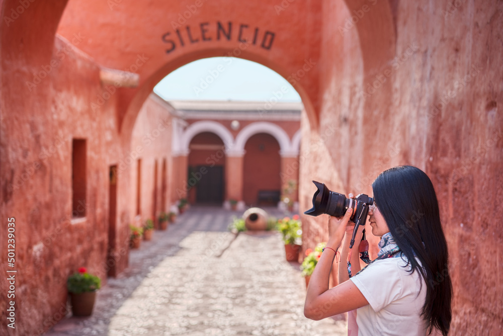 Turista latina fotografiando, con una cámara DSLR en el interior del monasterio Santa Catalina en Arequipa