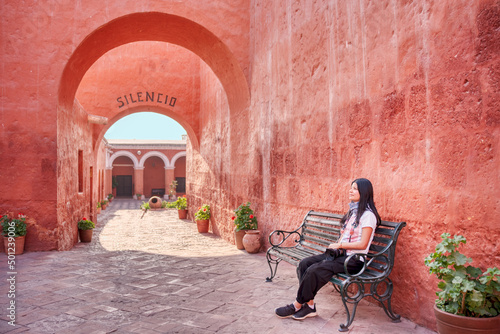 Joven turista sentada contemplando el arco de entrada del monasterio Santa Catalina en Arequipa