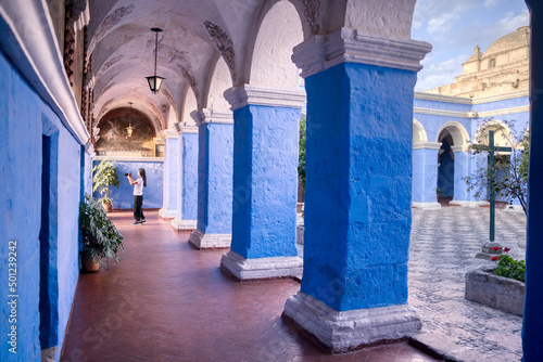 Turista latina fotografiando los pasillos del claustro de los naranjos del monasterio Santa Catalina en Arequipa photo