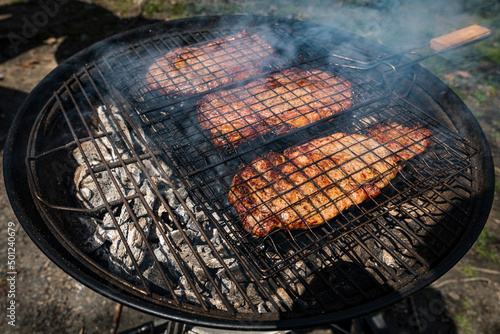 Selective focus of juicy beef steaks grilling on barbecue grid with smoke. High-quality photo