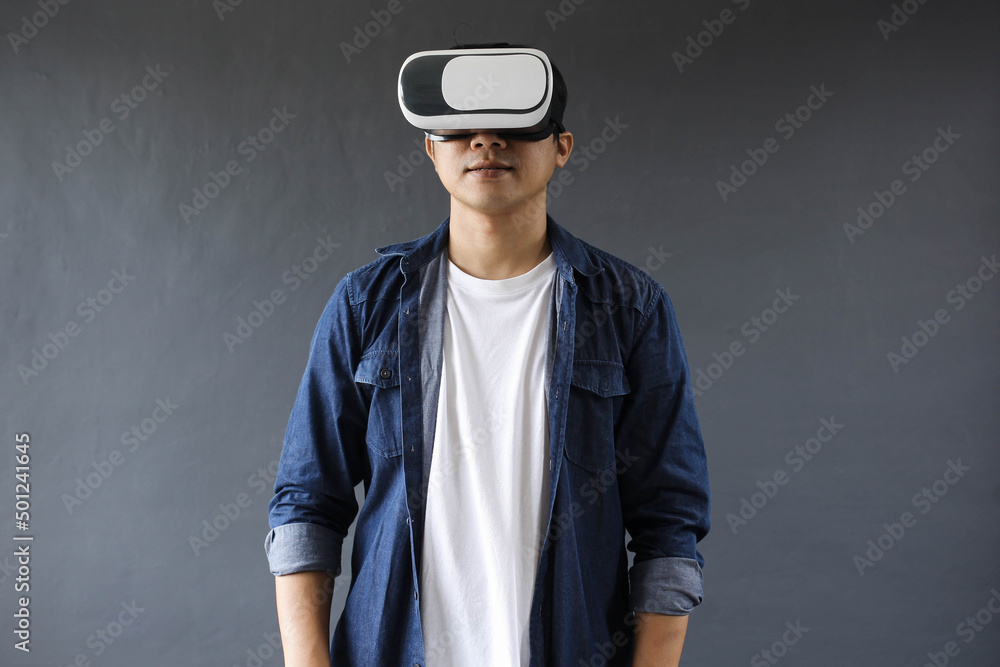 Young man using Virtual Reality googles on dark grey background. Young man using Virtual Reality googles on dark grey background.