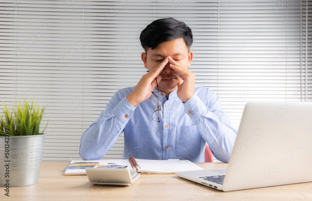 businessman is tired from working on his desk , feeling eyestrain, sitting at work desk, young man suffering from dry eye syndrome, fatigue after long laptop use and stress businessman is tired from working on his desk , feeling eyestrain, sitting at work desk, young man suffering from dry eye syndrome, fatigue after long laptop use and stress