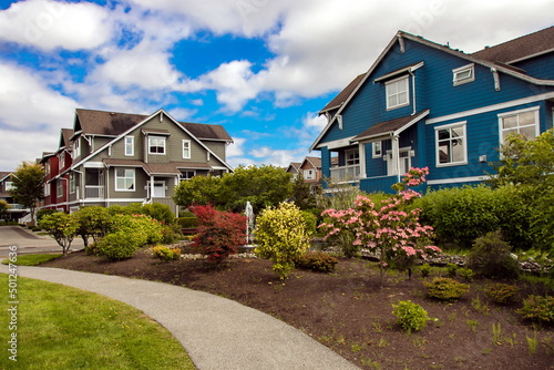 Residential District in Richmond City, a village of townhouses , green grass bushes and trees in the territory of residential complex, blue sky, Vanсouver, British Columbia  