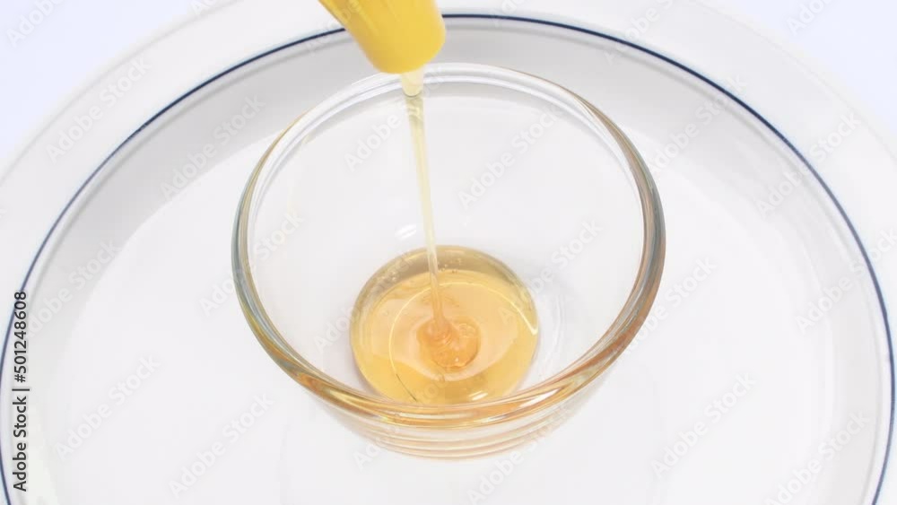 Honey purity pouring from a jar in a cup on white background.Color gold sweet food honey . Healthy food concept, food, dieting, organic natural bee products. Honey purity pouring from a jar in a cup on white background.Color gold sweet food honey . Healthy food concept, food, dieting, organic natural bee products.