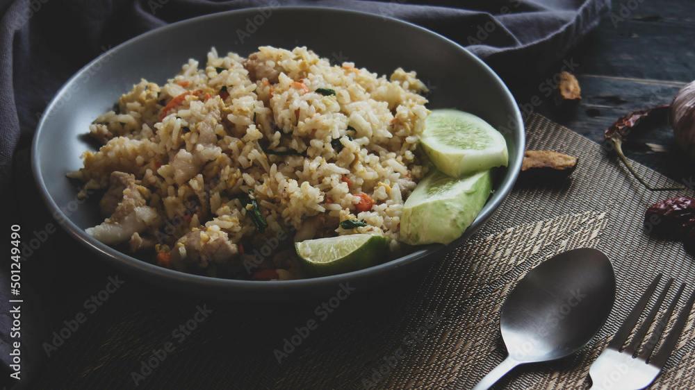 Pork fried rice is a common street food in Thailand. Served on a black wooden table. Pork fried rice is a common street food in Thailand. Served on a black wooden table.