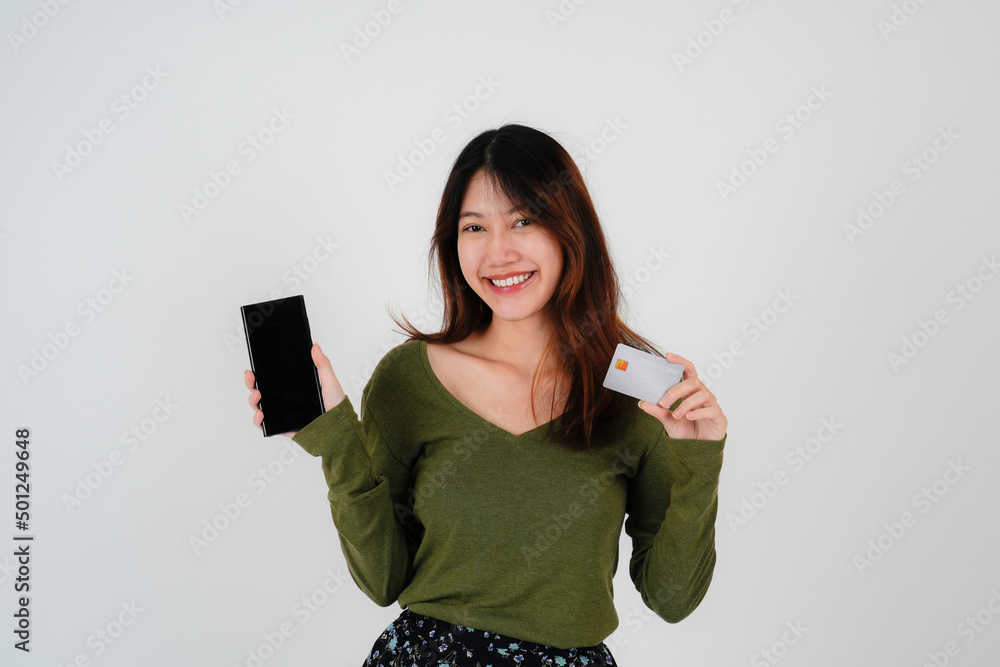 Naklejka premium Image of a beautiful young pretty woman posing isolated over white wall background using mobile phone holding credit card.