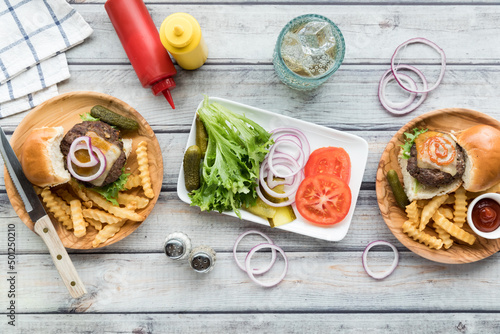 Sliders and fries on wooden plates with a platter of toppings in the middle. photo