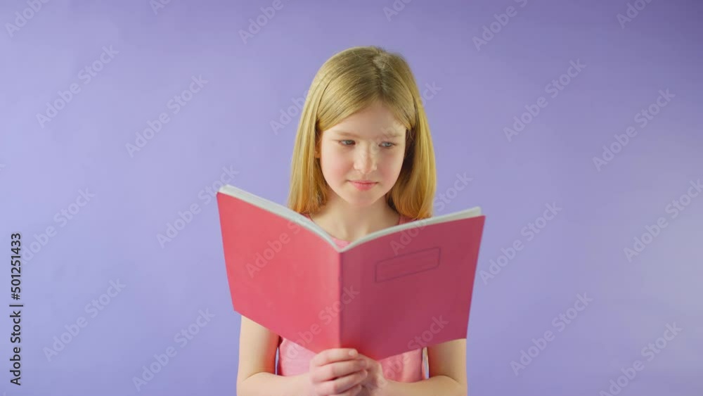 Studio Shot Of Young Girl Studying School Exercise Book Against Purple Background Studio Shot Of Young Girl Studying School Exercise Book Against Purple Background