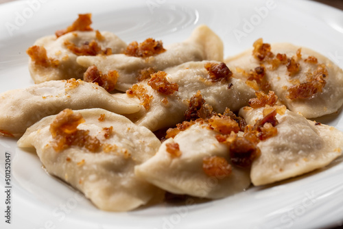 Traditional ukrainian dish vareniki served in a bowl with greaves and sour cream. Close up view of traditional Ukrainian food. photo