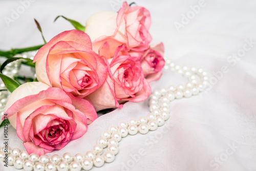The branch of pink rose on white fabric background 