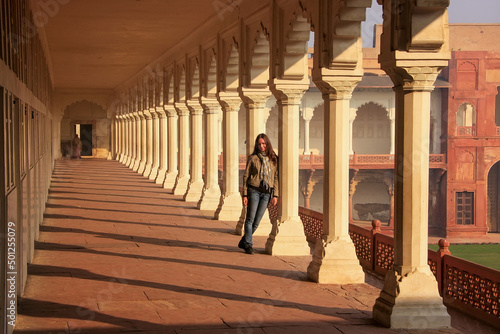 Young woman standing in colonnade walkway leading to Diwan-i- Khas in Agra Fort, Uttar Pradesh, India