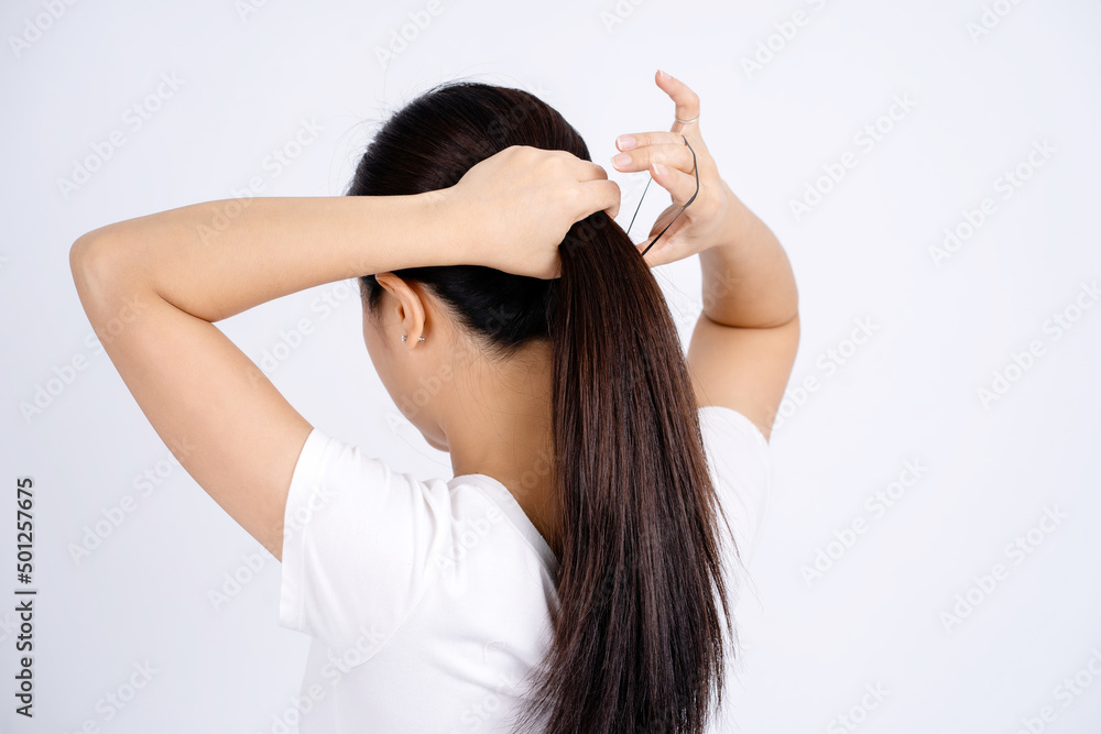 Asian woman tying her hair up isolated on a white background. Asian woman tying her hair up isolated on a white background.