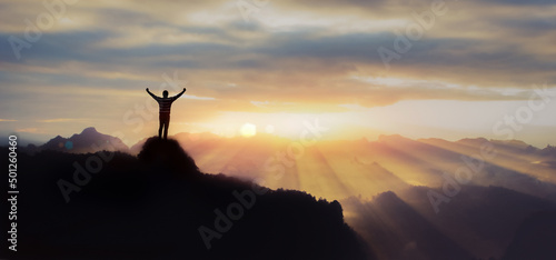 A man raising his hands for victory on the top of a mountain