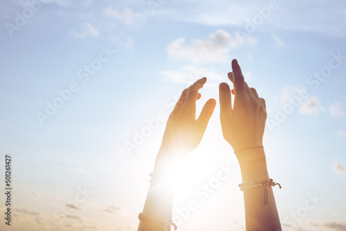 Female lifting hands up to sunset sky