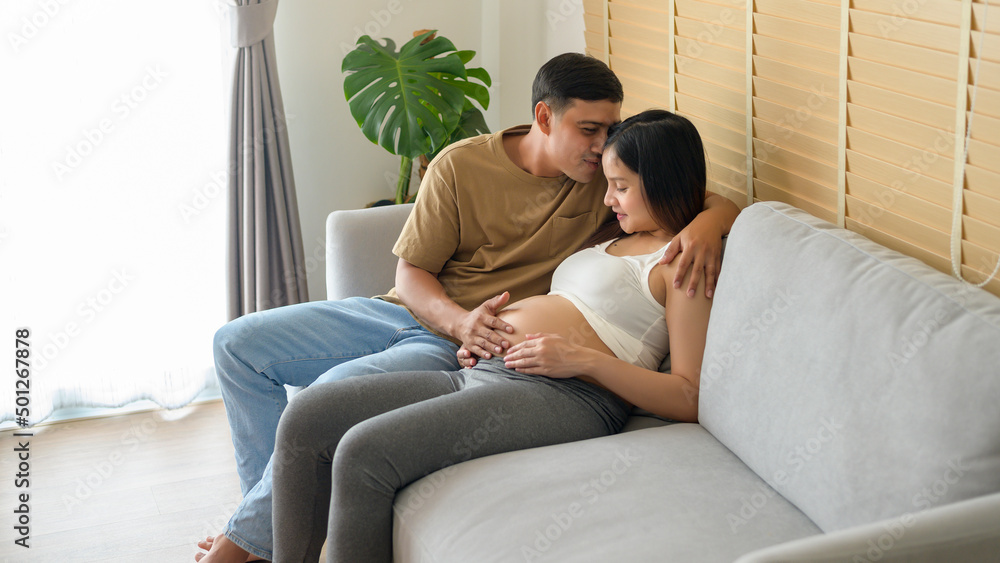 Young pregnant woman with husband embracing and expecting a baby at home Young pregnant woman with husband embracing and expecting a baby at home