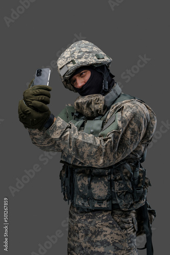 Shot of cheerful military man dressed in modern camouflage uniform taking selfie. Information warfare.