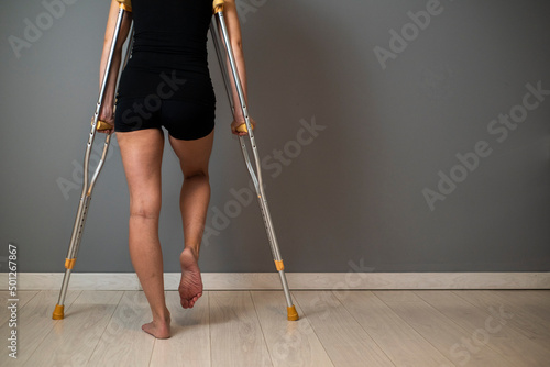 Принти на полотні Woman with injured leg using crutches on grey background, closeup