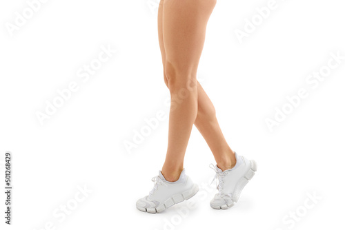 Cropped photo of athletic and muscular women's legs in sneakers walking