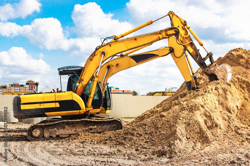 Two powerful excavators work at the same time on a construction site, sunny blue sky in the background. Construction equipment for earthworks. Two powerful excavators work at the same time on a construction site, sunny blue sky in the background. Construction equipment for earthworks.