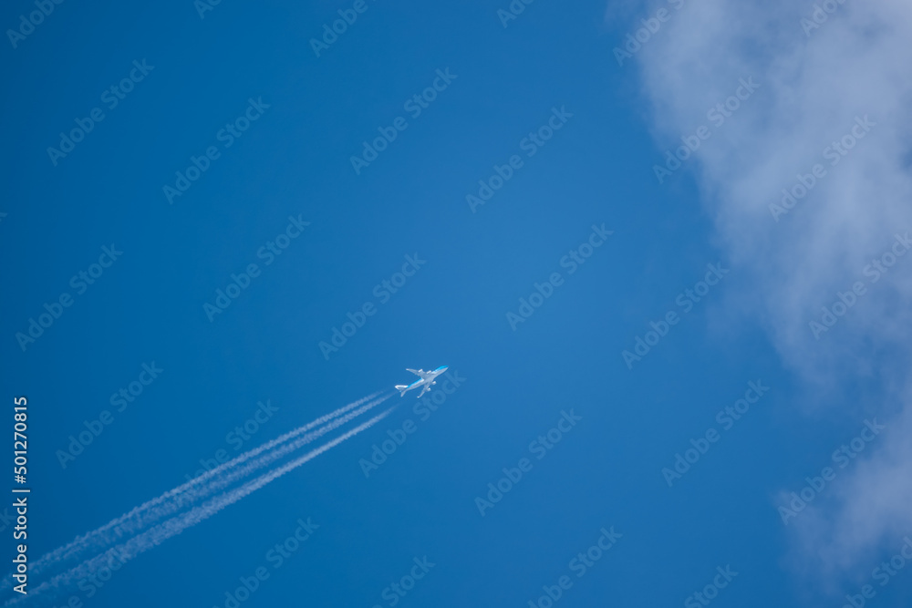 diagonal lower left to upper right high altitude contrails from a four engine KLM Boeing 747-400 Cargo Jumbo jet aircraft entering cloud blue sky diagonal lower left to upper right high altitude contrails from a four engine KLM Boeing 747-400 Cargo Jumbo jet aircraft entering cloud blue sky
