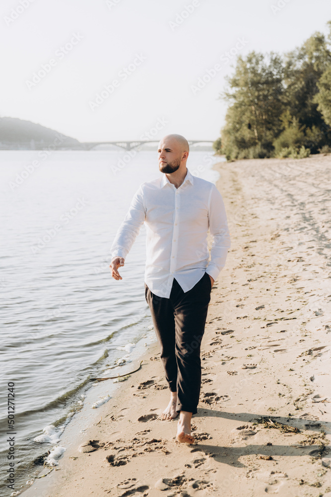 Wedding photosession at sunset of a beautiful couple, the bride in a white dress, and the groom in a white shirt and black trousers Wedding photosession at sunset of a beautiful couple, the bride in a white dress, and the groom in a white shirt and black trousers