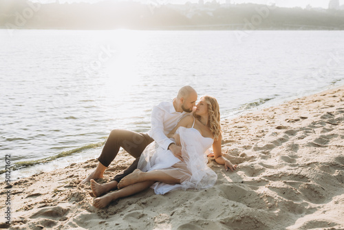 Wedding photosession at sunset of a beautiful couple, the bride in a white dress, and the groom in a white shirt and black trousers