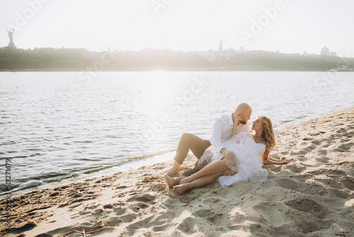Wedding photosession at sunset of a beautiful couple, the bride in a white dress, and the groom in a white shirt and black trousers © Олег Блохин
